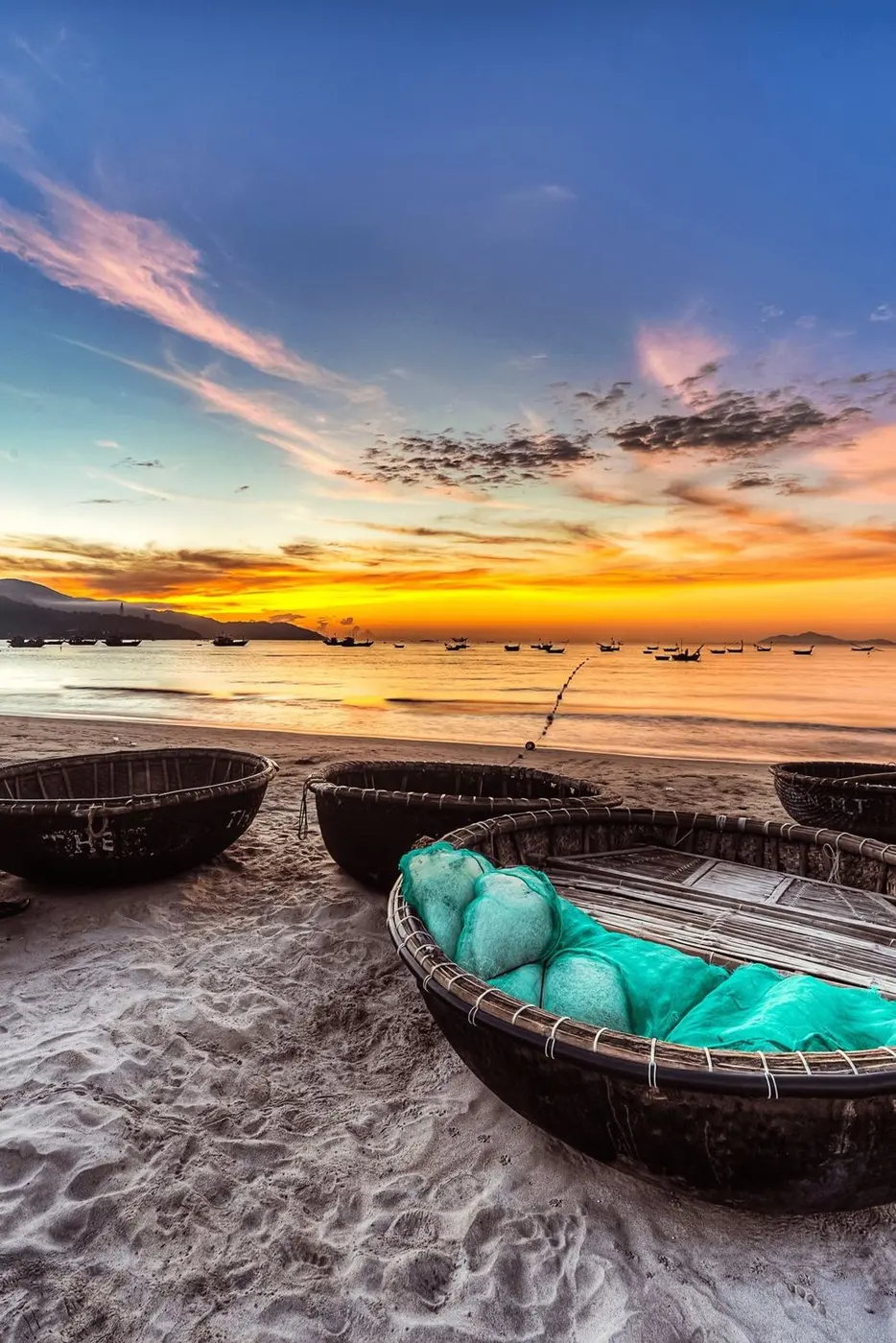 Круглые плетёные лодки на песчаном пляже на закате
