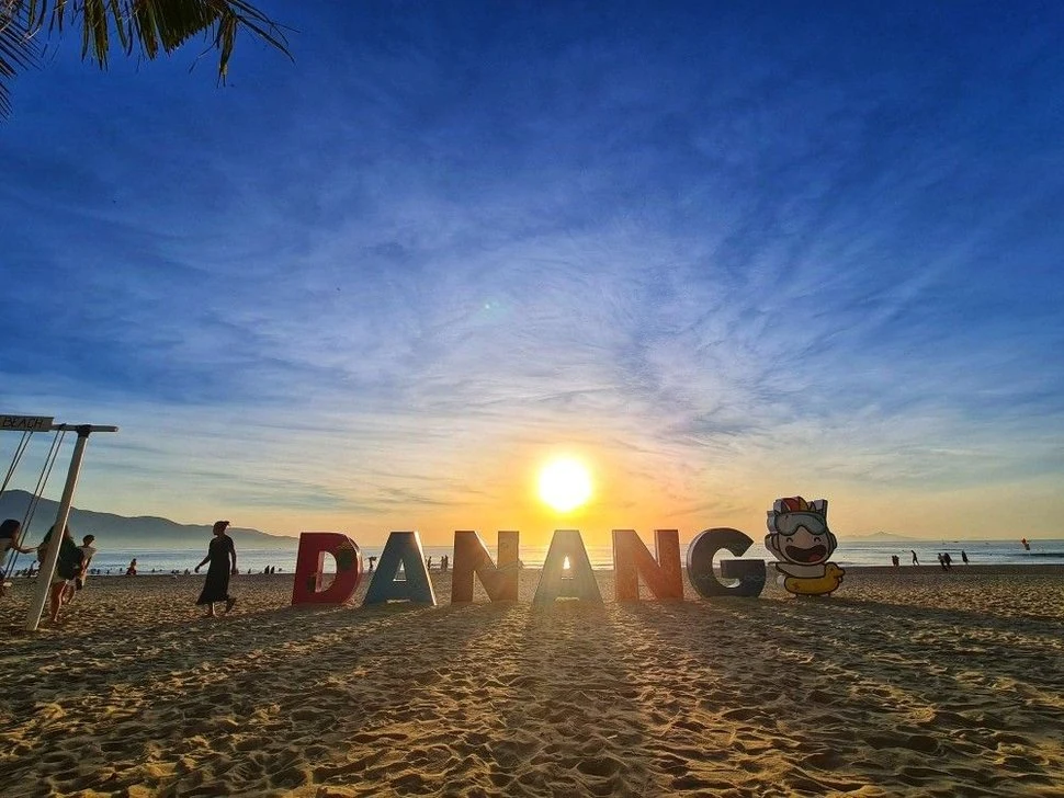 Рассвет на пляже Дананга с крупными разноцветными буквами DANANG на песке